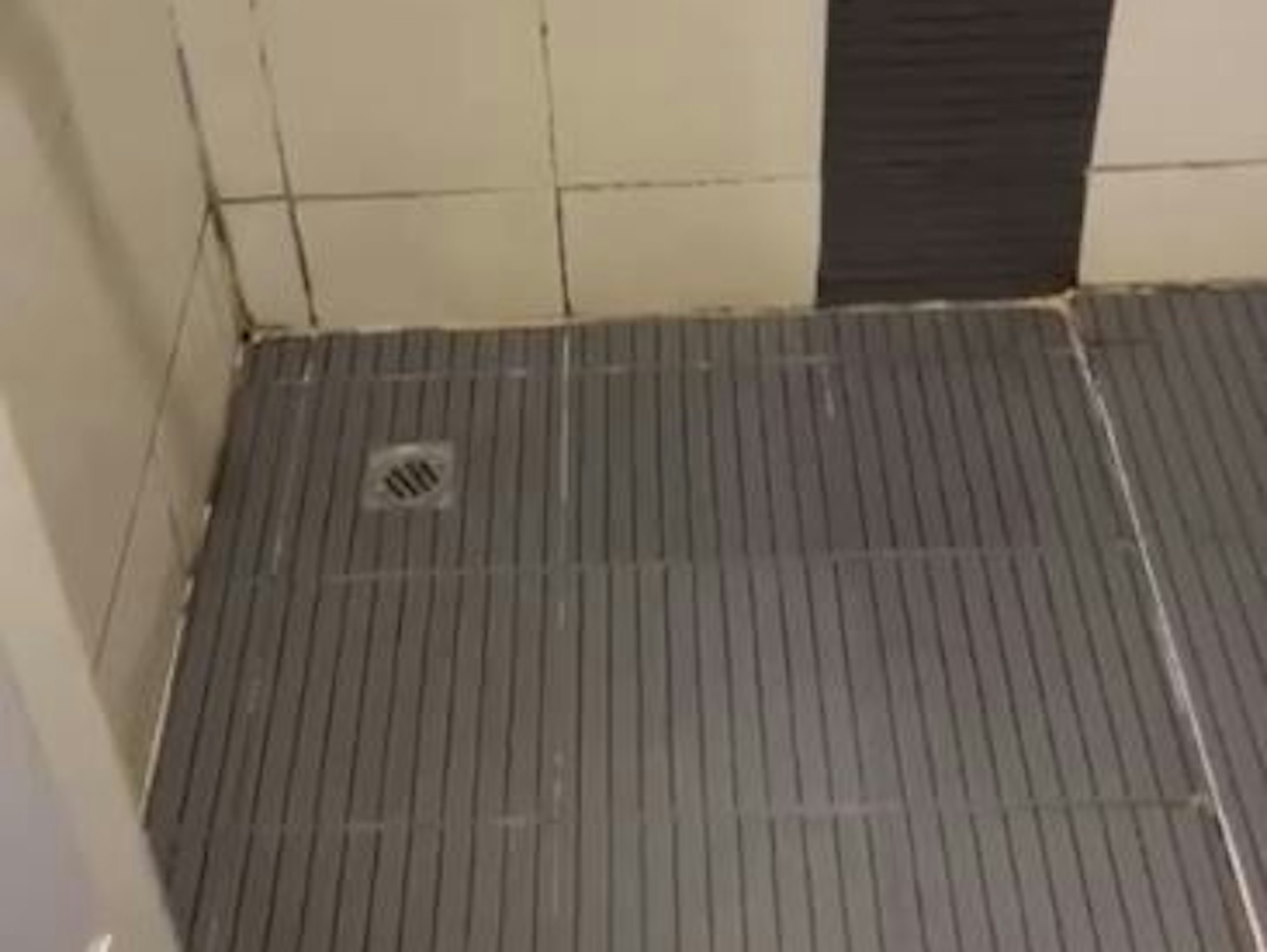 Blick in die Dusche eines Hotels. Dort sind Schimmel und ein verdreckter Abfluss zu sehen.