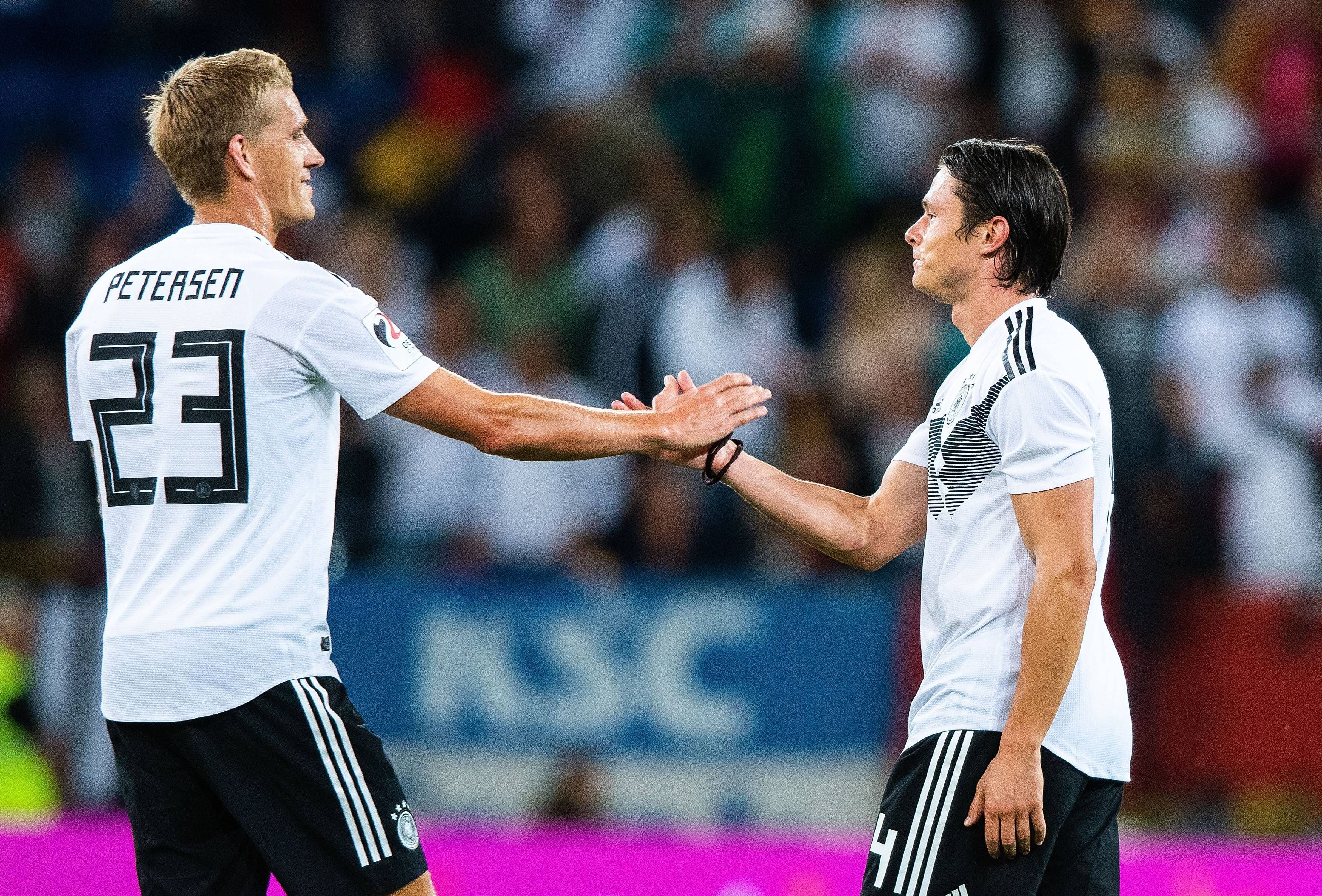 Nils Petersen klatscht mit Nico Schulz im Trikot der deutschen Nationalmannschaft ab.