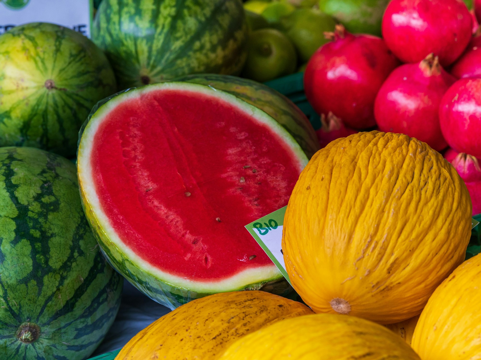 Melonen, Granatäpfel und Birnen liegen nebeneinander.