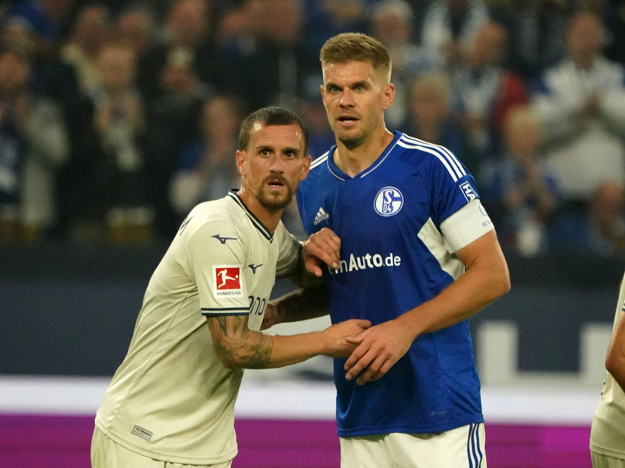 Simon Zoller und Simon Terodde warten auf eine Hereingabe und berühren sich mit ihren Händen.