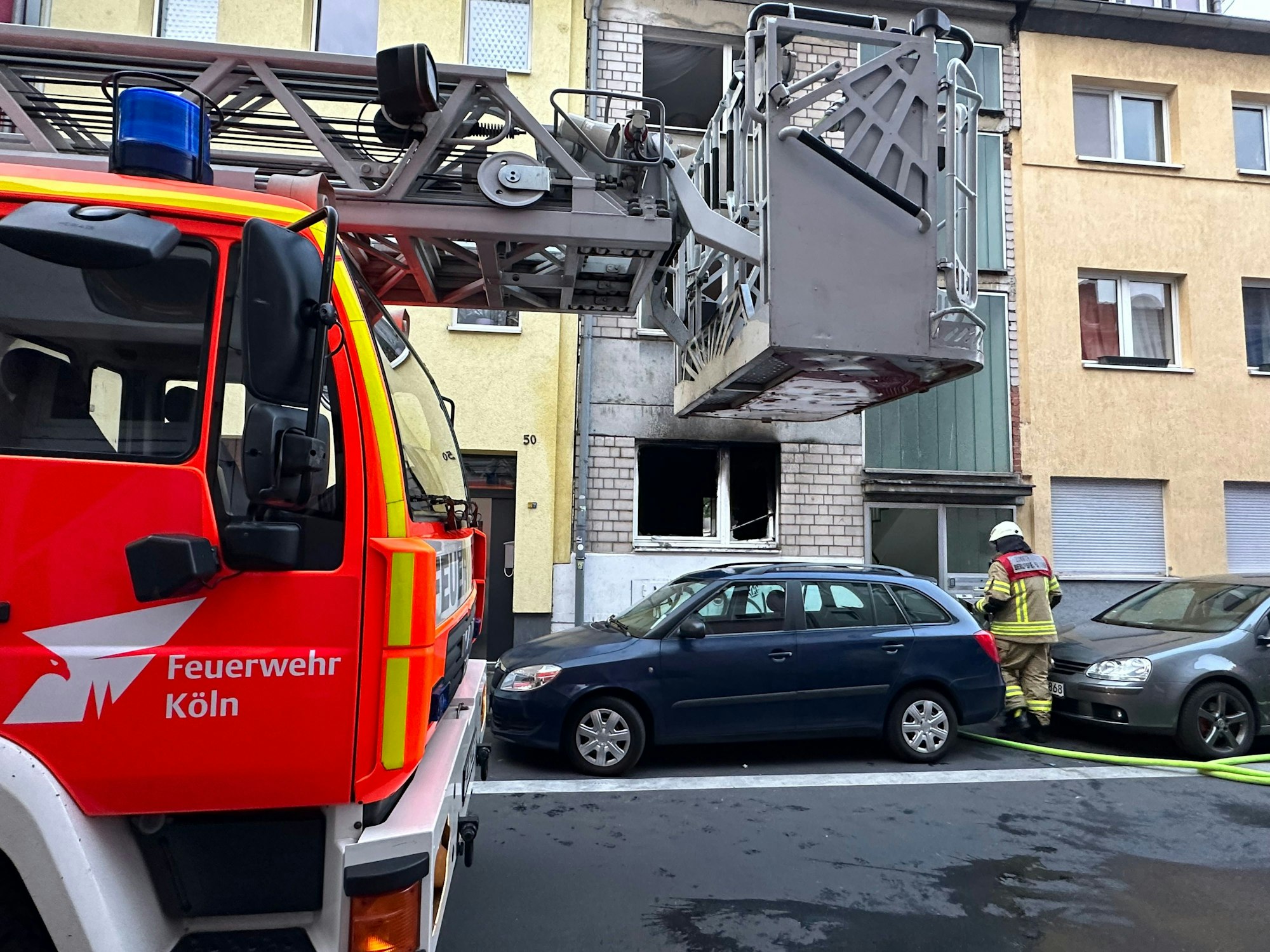 Feuerwehr-Wagen an einer Straße vor einer ausgebrannten Wohnung.