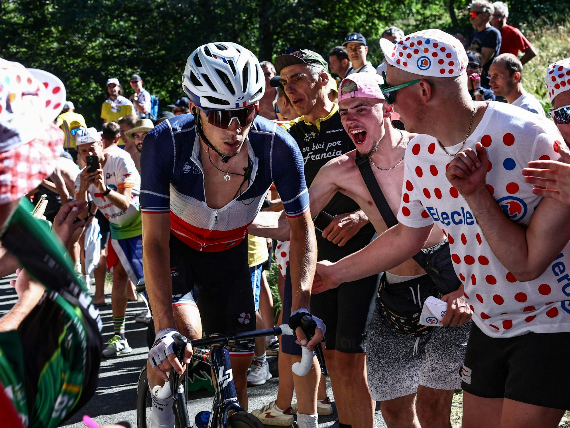 Valentin Madouas fährt bei der Tour de France zwischen jubelnden Fans einen Anstieg hoch.