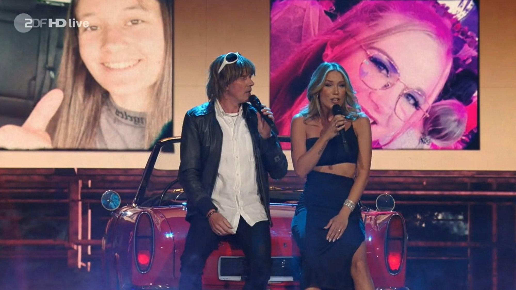 Mickie Krause und Sonia Liebing sitzen auf einem Auto.