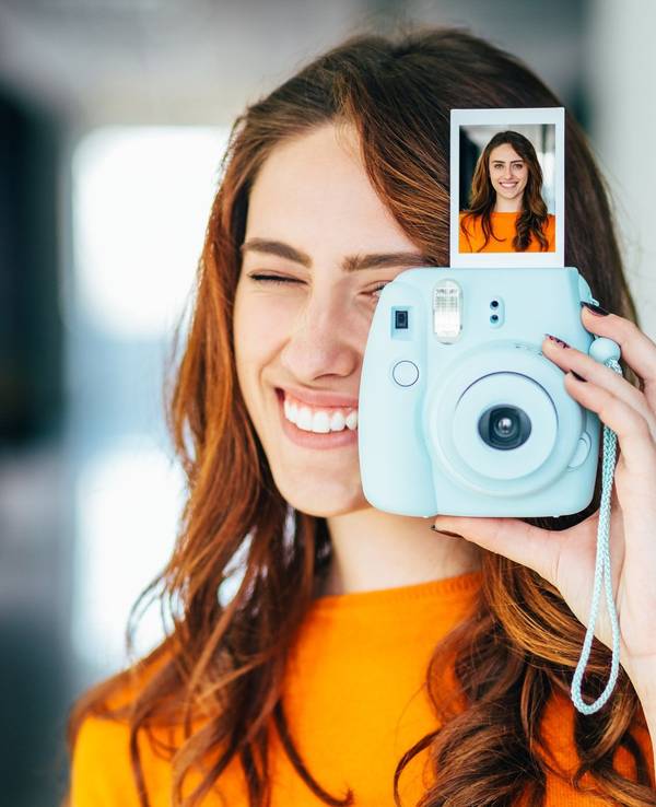 Frau hält Sofortbild-Kamera mit Bild in der Hand