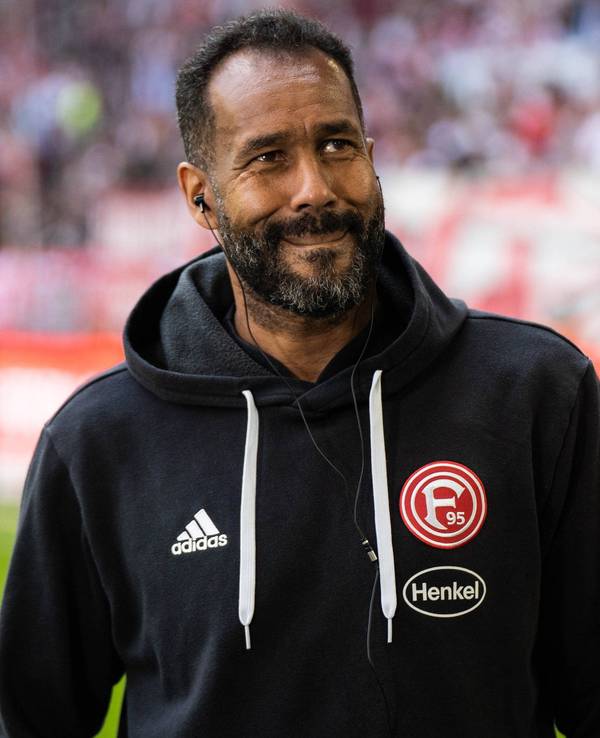 Daniel Thioune blickt verschmitzt auf die Tribüne.