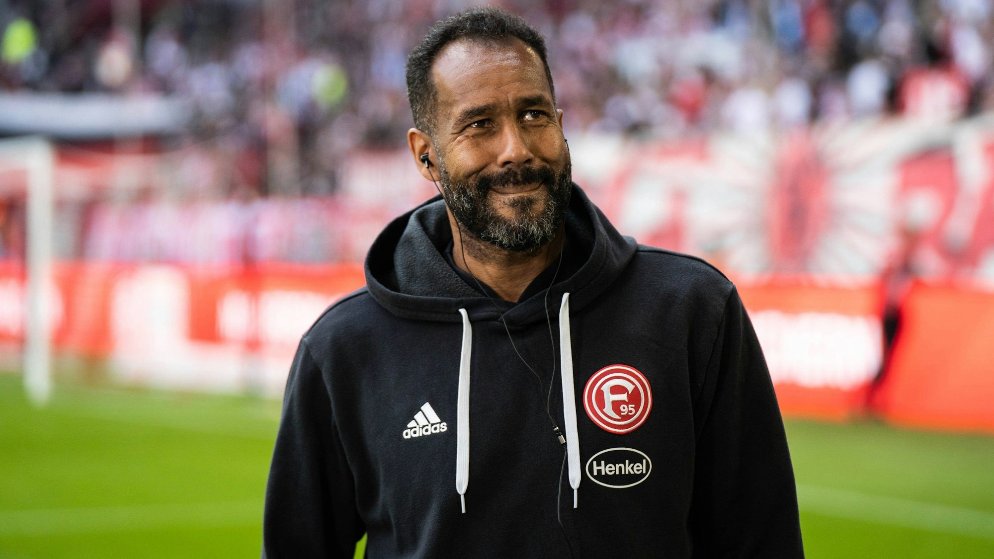 Daniel Thioune blickt verschmitzt auf die Tribüne.