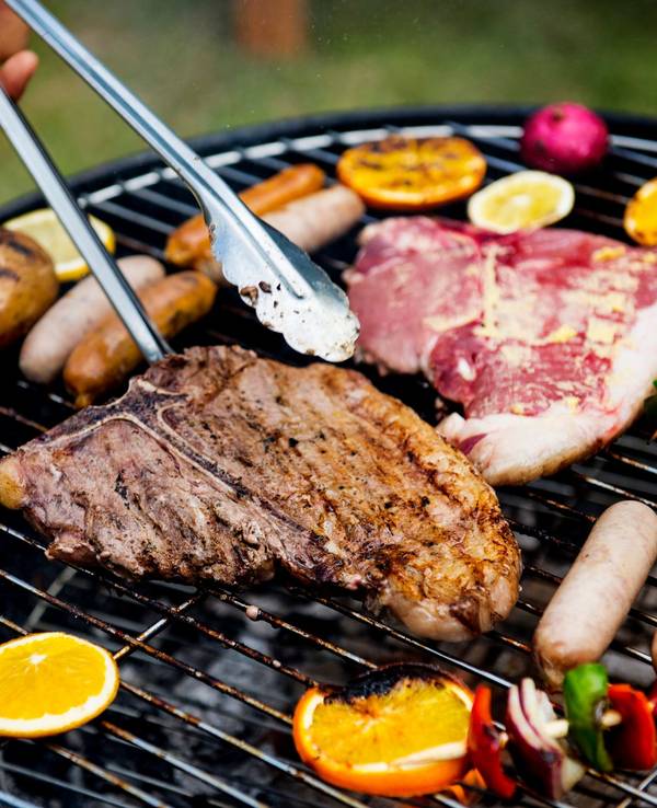 Auf einem Grill wird Fleisch und Gemüse gegrillt.