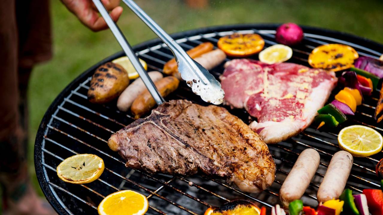 Auf einem Grill wird Fleisch und Gemüse gegrillt.