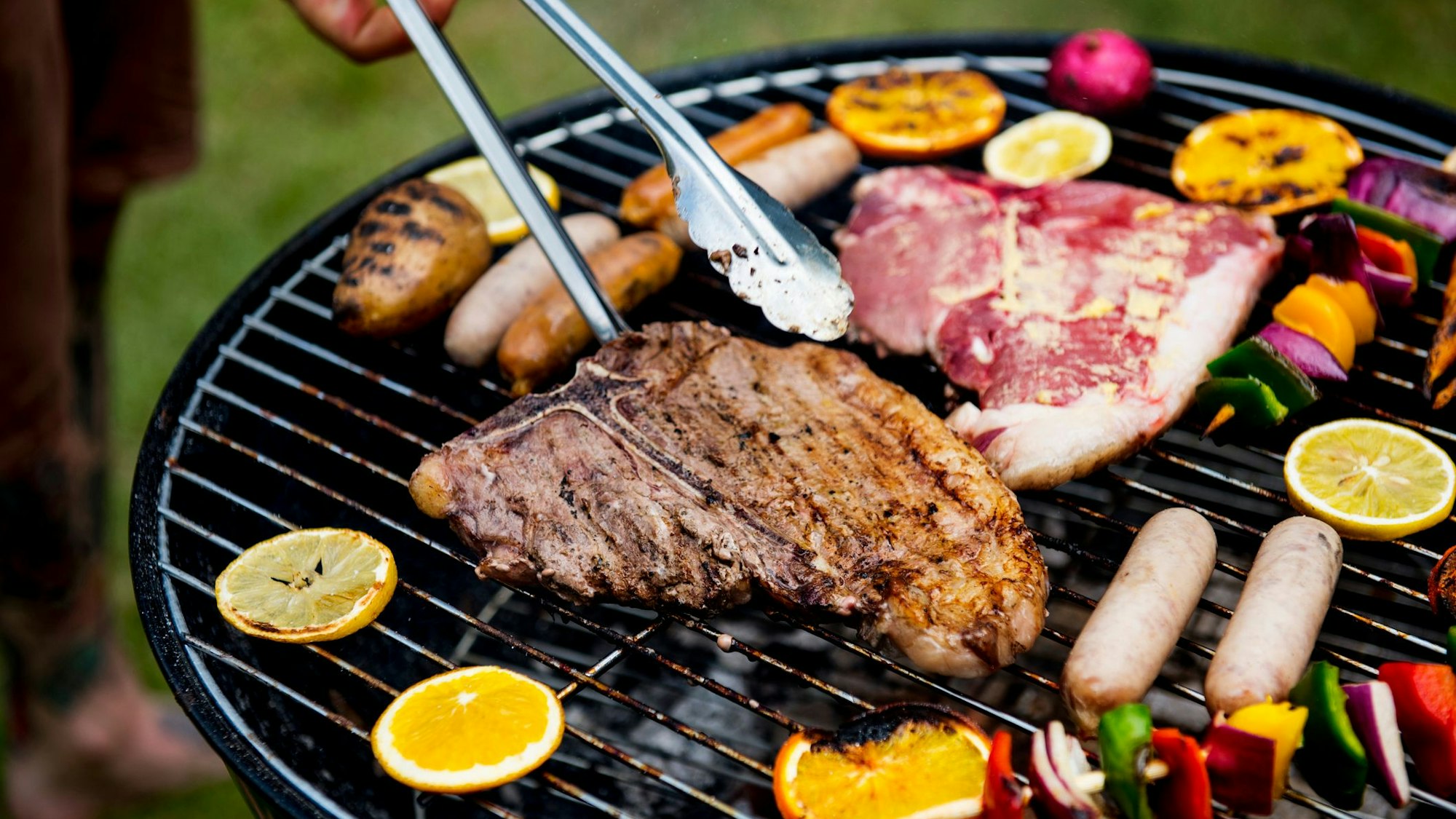 Auf einem Grill wird Fleisch und Gemüse gegrillt.