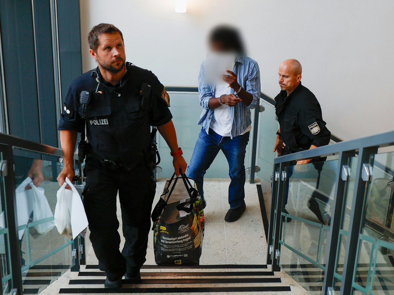 Der Angeklagte (M) wird von der Polizei in Handschellen zum Gerichtssaal, im Landgericht Aschaffenburg gebracht.