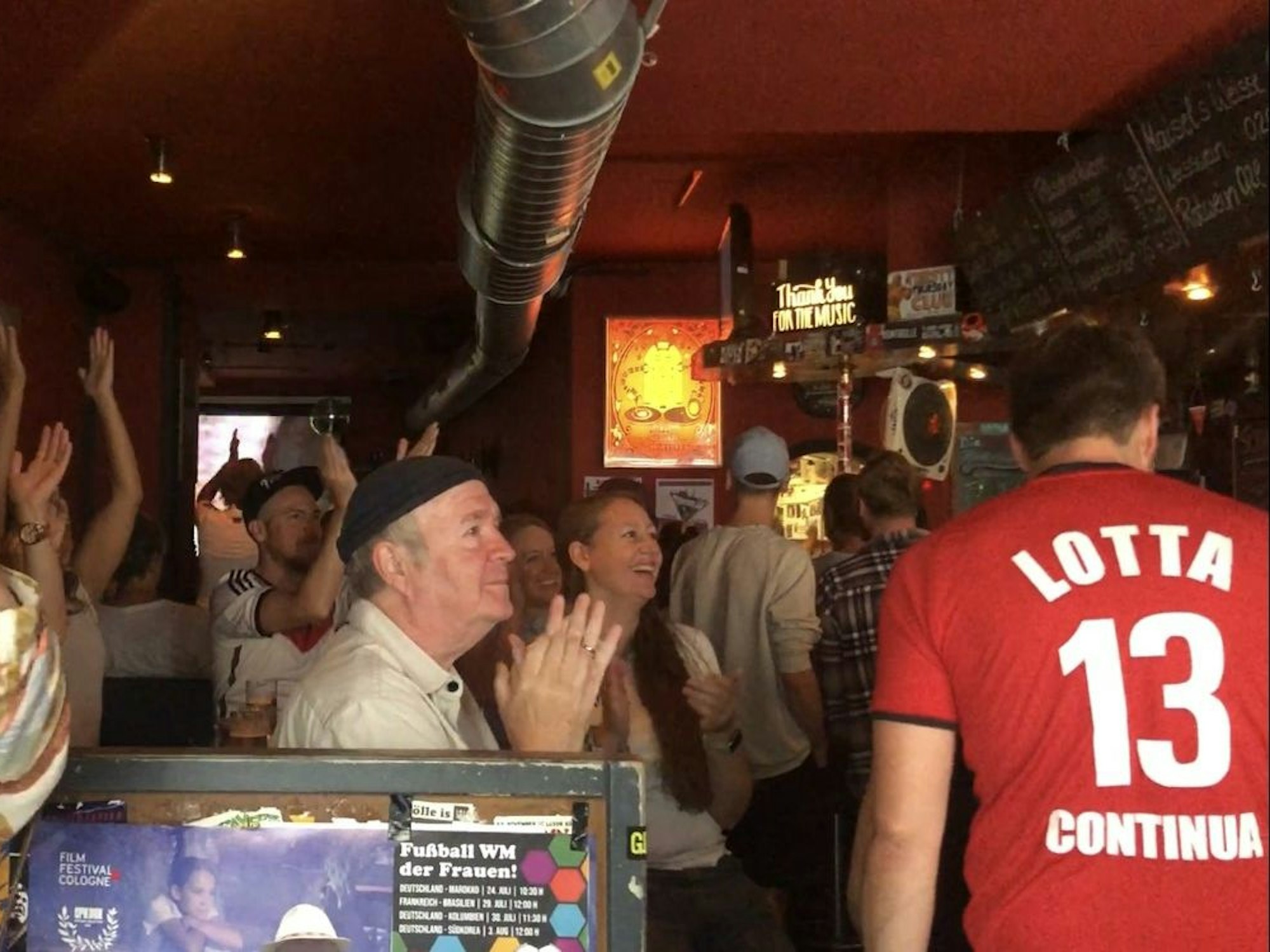 Menschen jubeln in einer Kneipe.