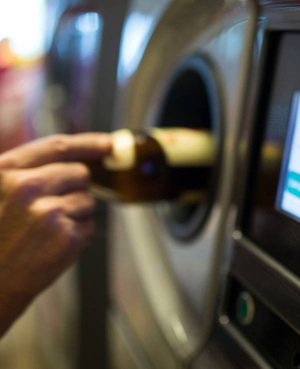 Eine Person gibt in Berlin Pfandflaschen an einem Pfandflaschenautomaten ab, hier im April 2015.