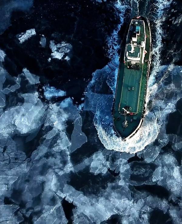 Ein Schiff fährt durch die Antarktis und schiebt Eisschollen vor sich her.