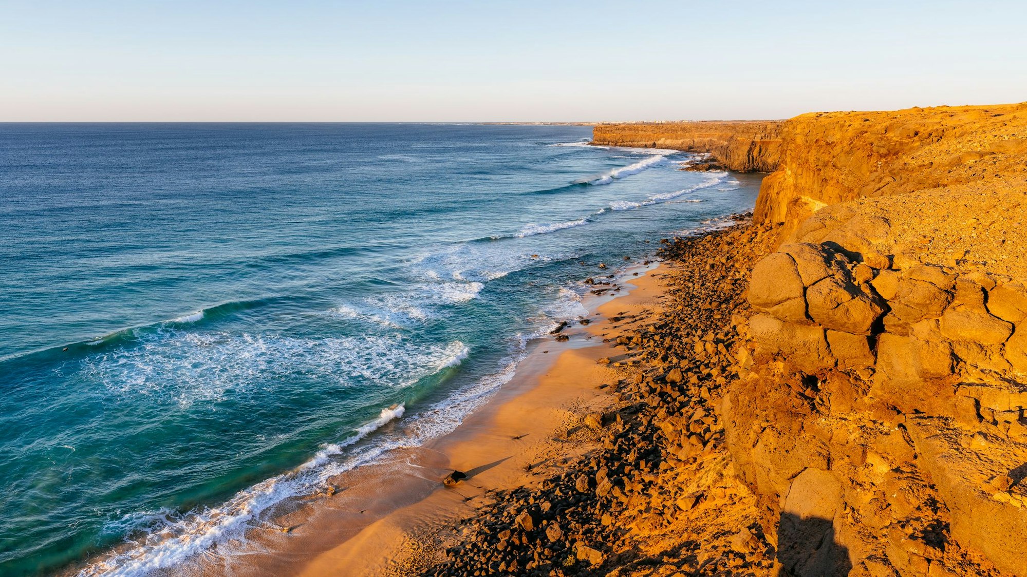 Karger Fels trifft auf raues Meer bei Sonnenuntergang.