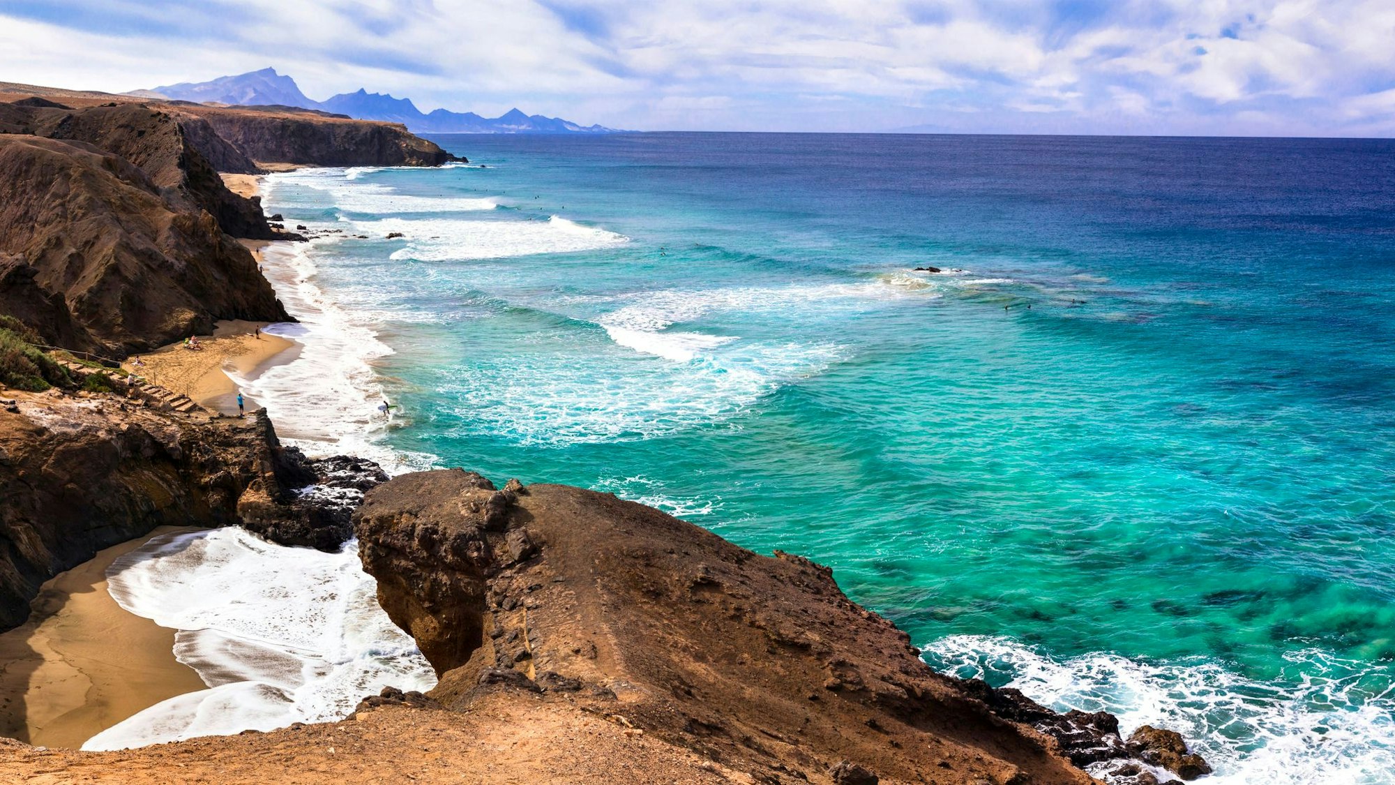 Braune Klippen treffen auf türkisfarbenes Meer.
