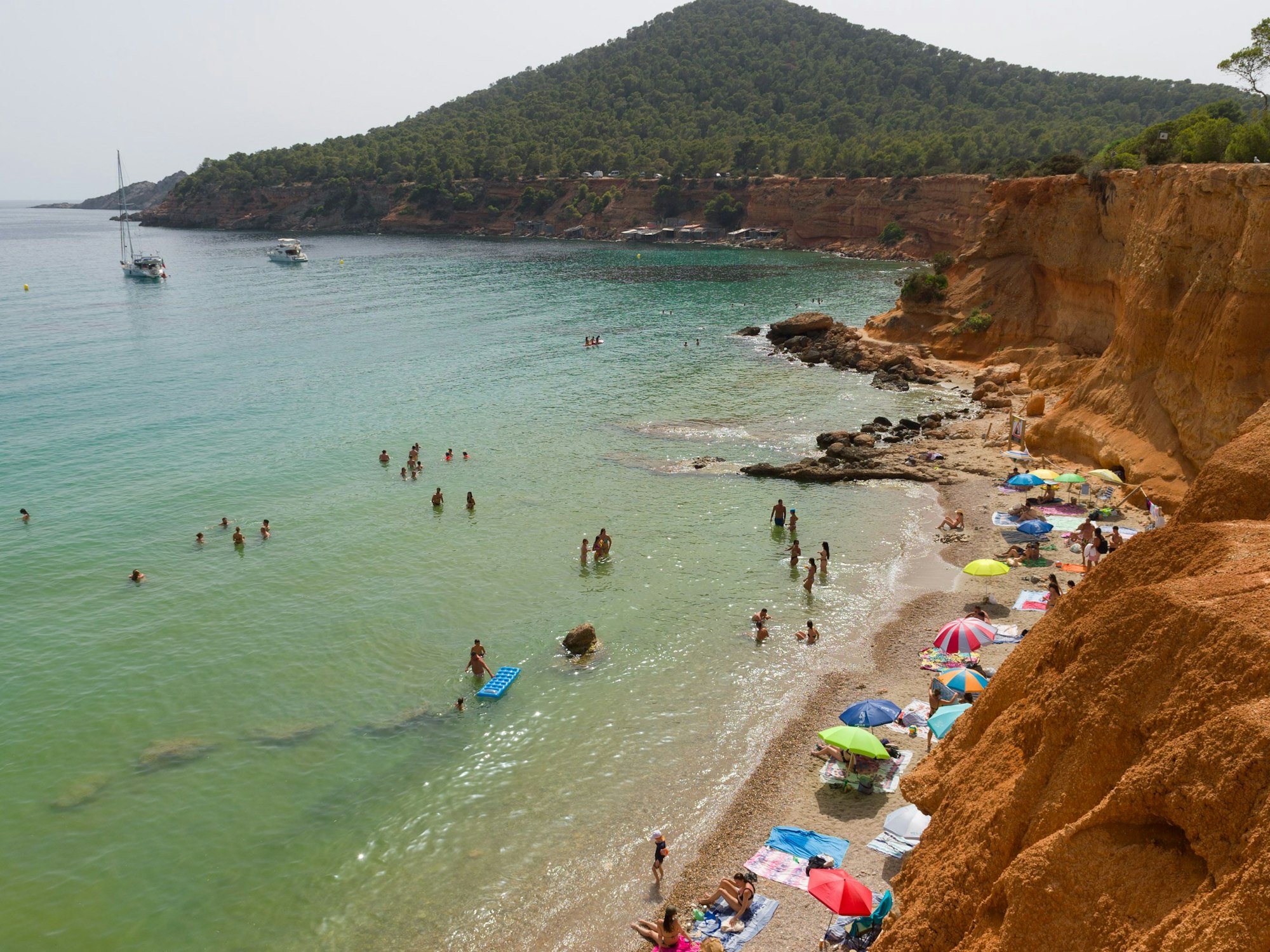 Menschen genießen einen Tag am Strand Es Bol Nou auf Ibiza, hier im Juli 2023.