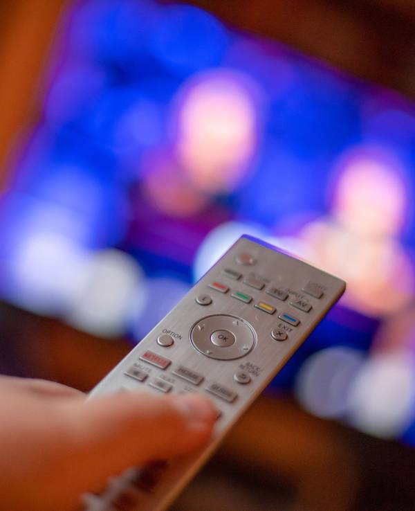 Ein Mann bedient mit der Fernbedienung einen Fernseher.