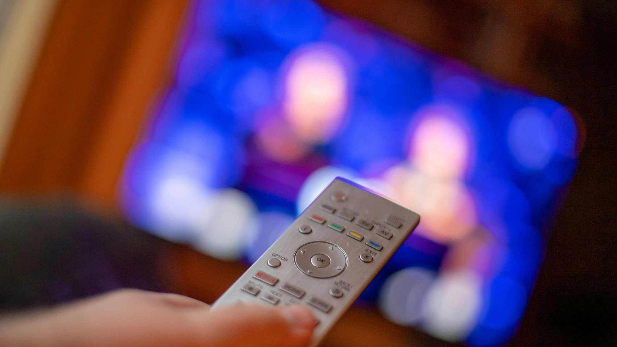 Ein Mann bedient mit der Fernbedienung einen Fernseher.