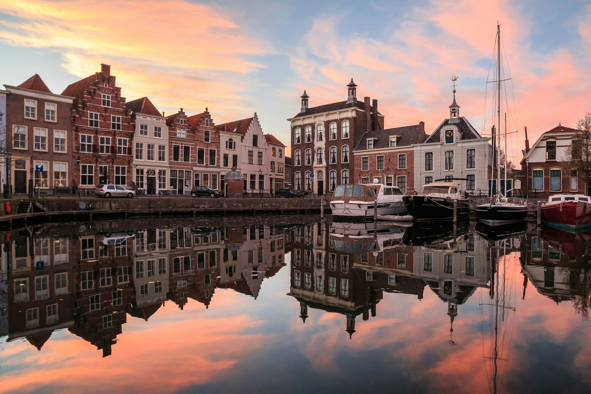 Boote liegen im kleinen Hafen der Stadt Goes in Zeeland. Über dem Ort geht die Sonne unter.