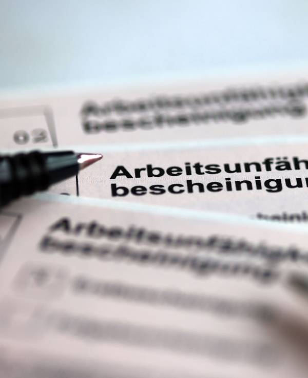 Stifte liegen auf den Arbeitsunfähigkeitsbescheinigungen für Arbeitnehmer im Falle einer Krankschreibung durch den Arzt.