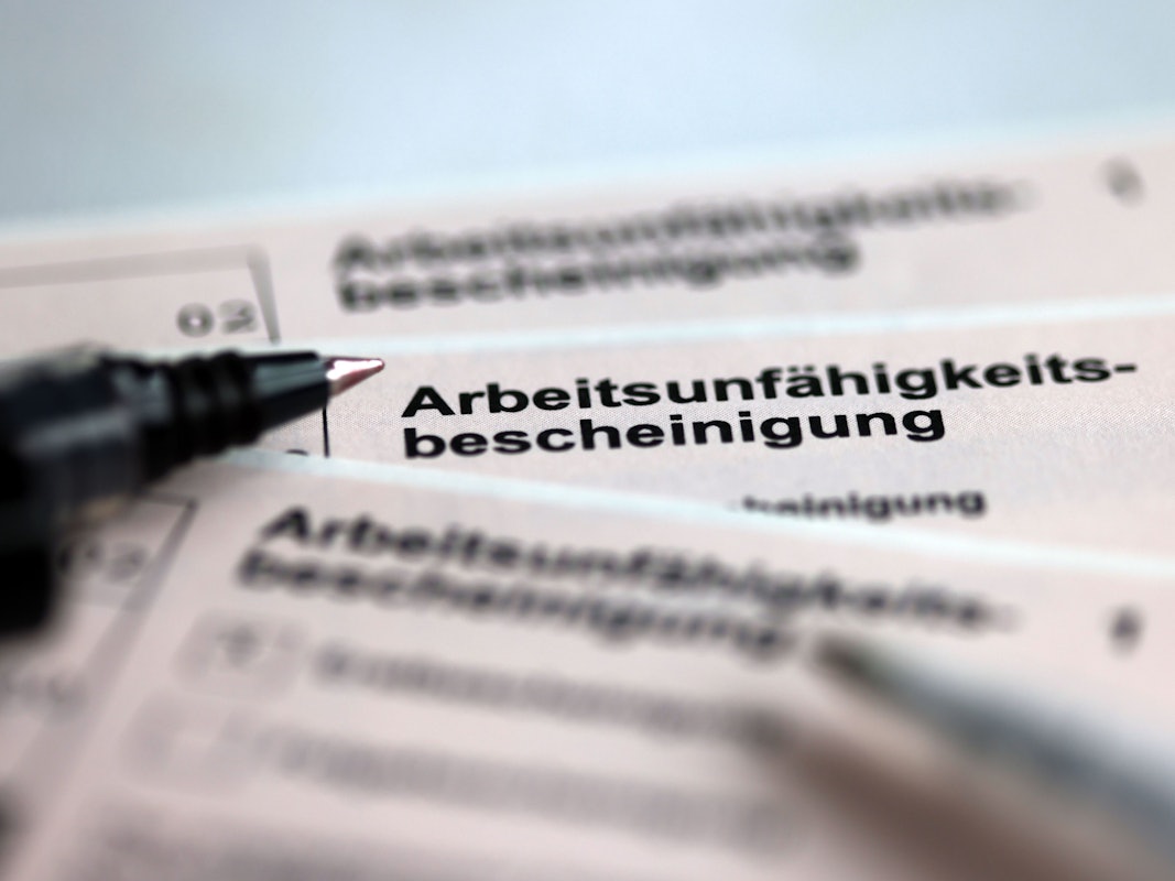 Stifte liegen auf den Arbeitsunfähigkeitsbescheinigungen für Arbeitnehmer im Falle einer Krankschreibung durch den Arzt.