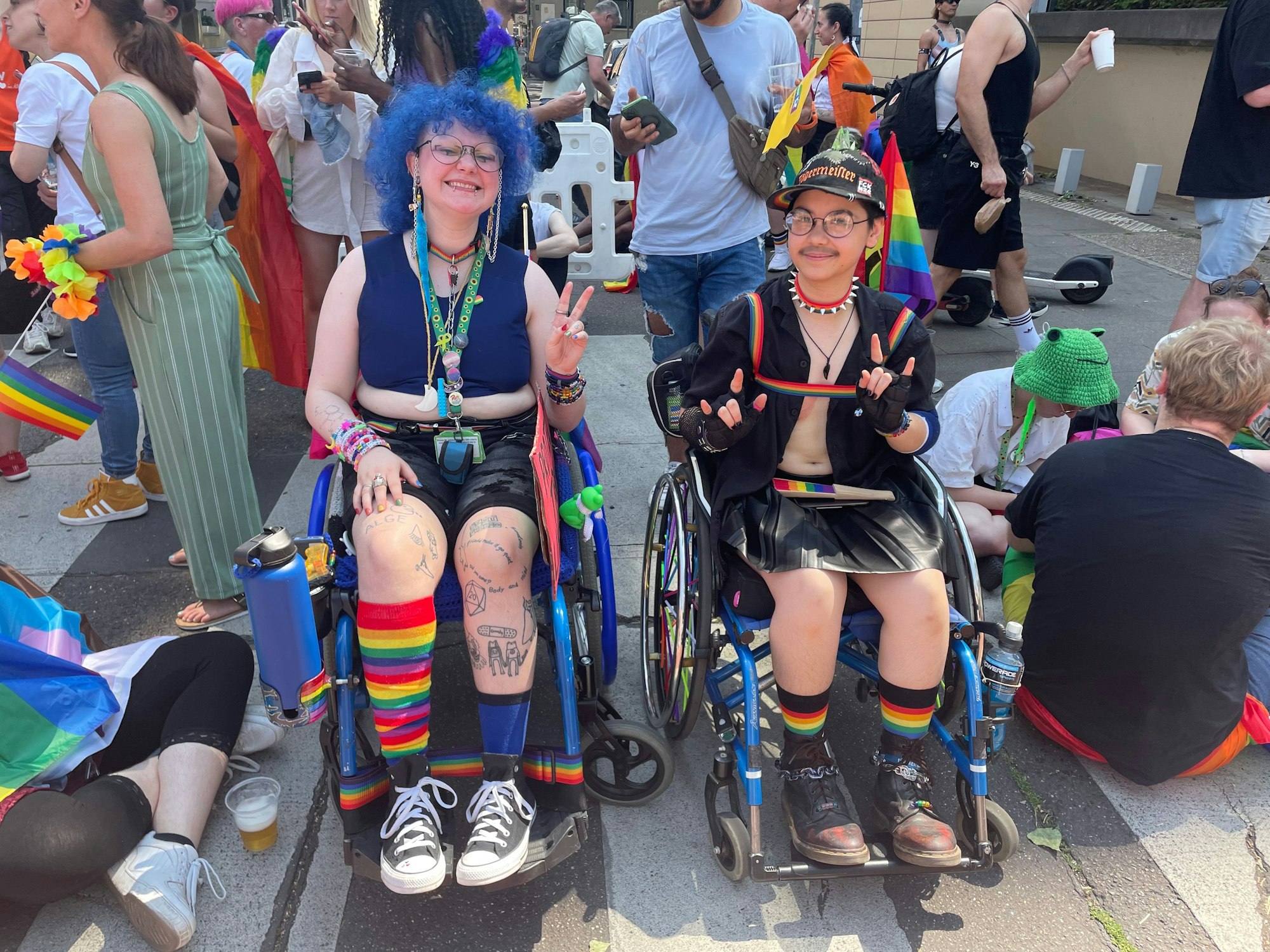 Mio und Panic sitzen im Rollstuhl und feiern beim CSD Köln.