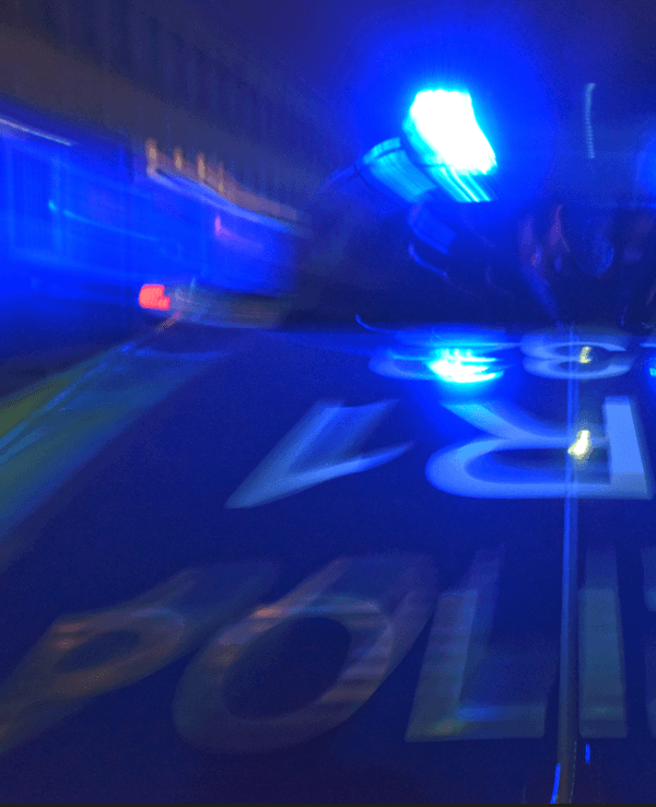 Ein Polizeifahrzeug steht mit Blaulicht auf der Straße.