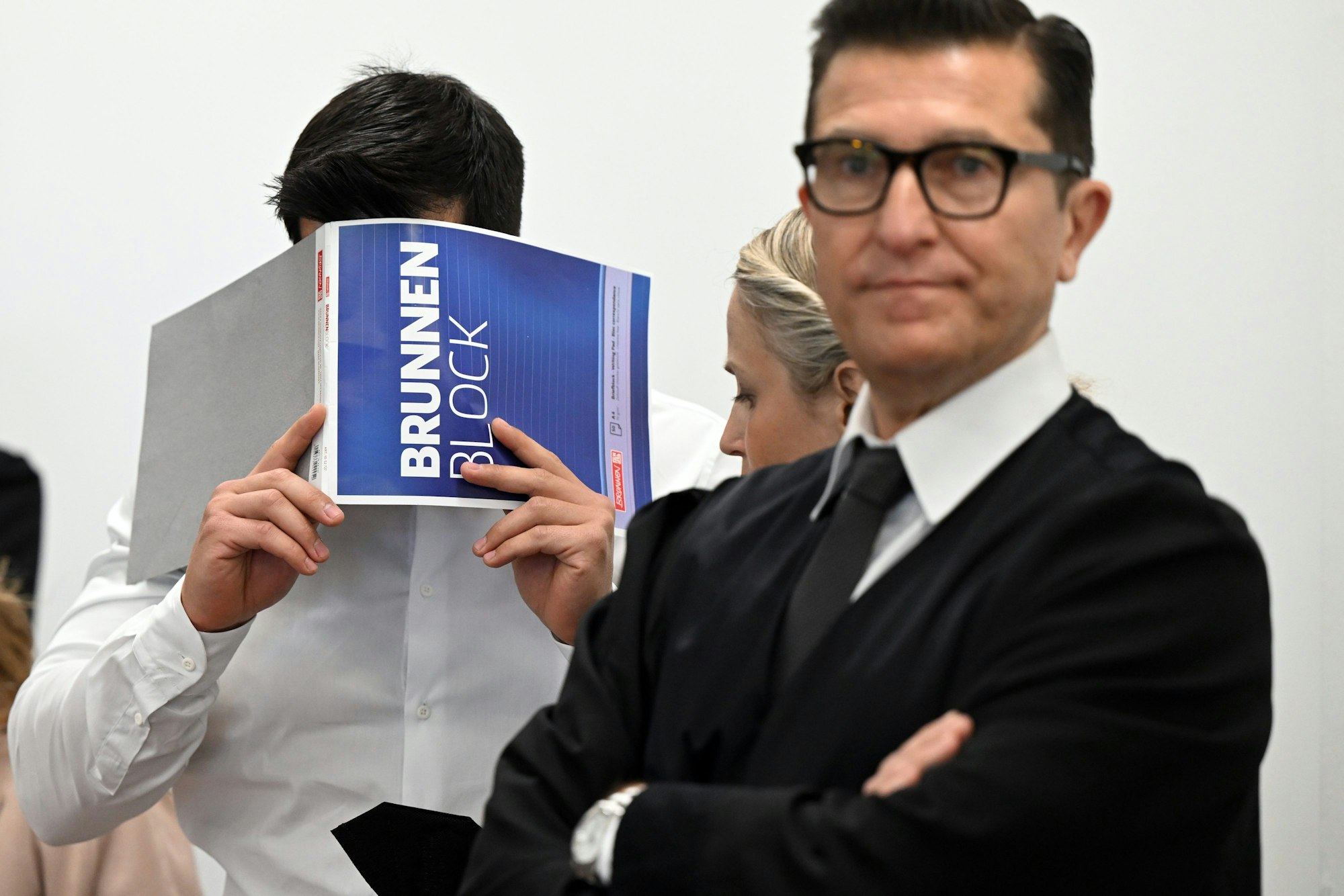 Der Angeklagte hält sich im Gerichtsaal einen Block vor das Gesicht.