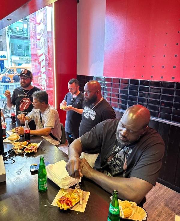Shaquille O'Neal isst eine Pommes mit Wurst