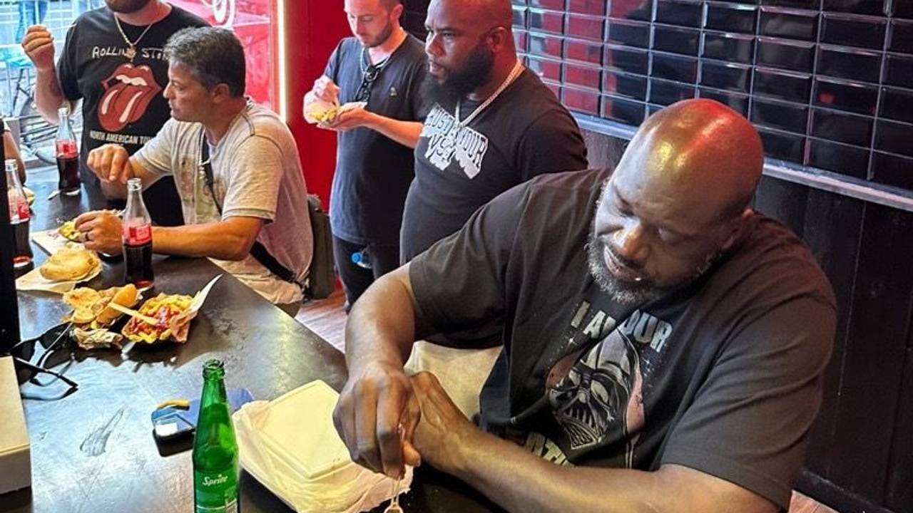 Shaquille O'Neal isst eine Pommes mit Wurst