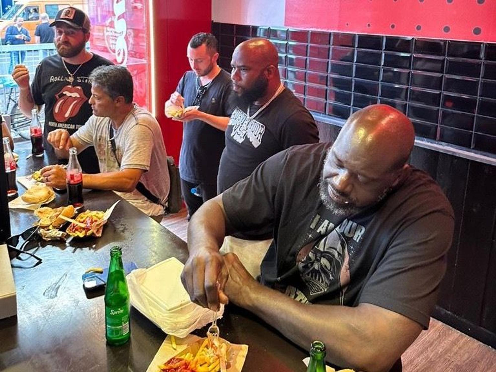 Shaquille O'Neal isst eine Pommes mit Wurst
