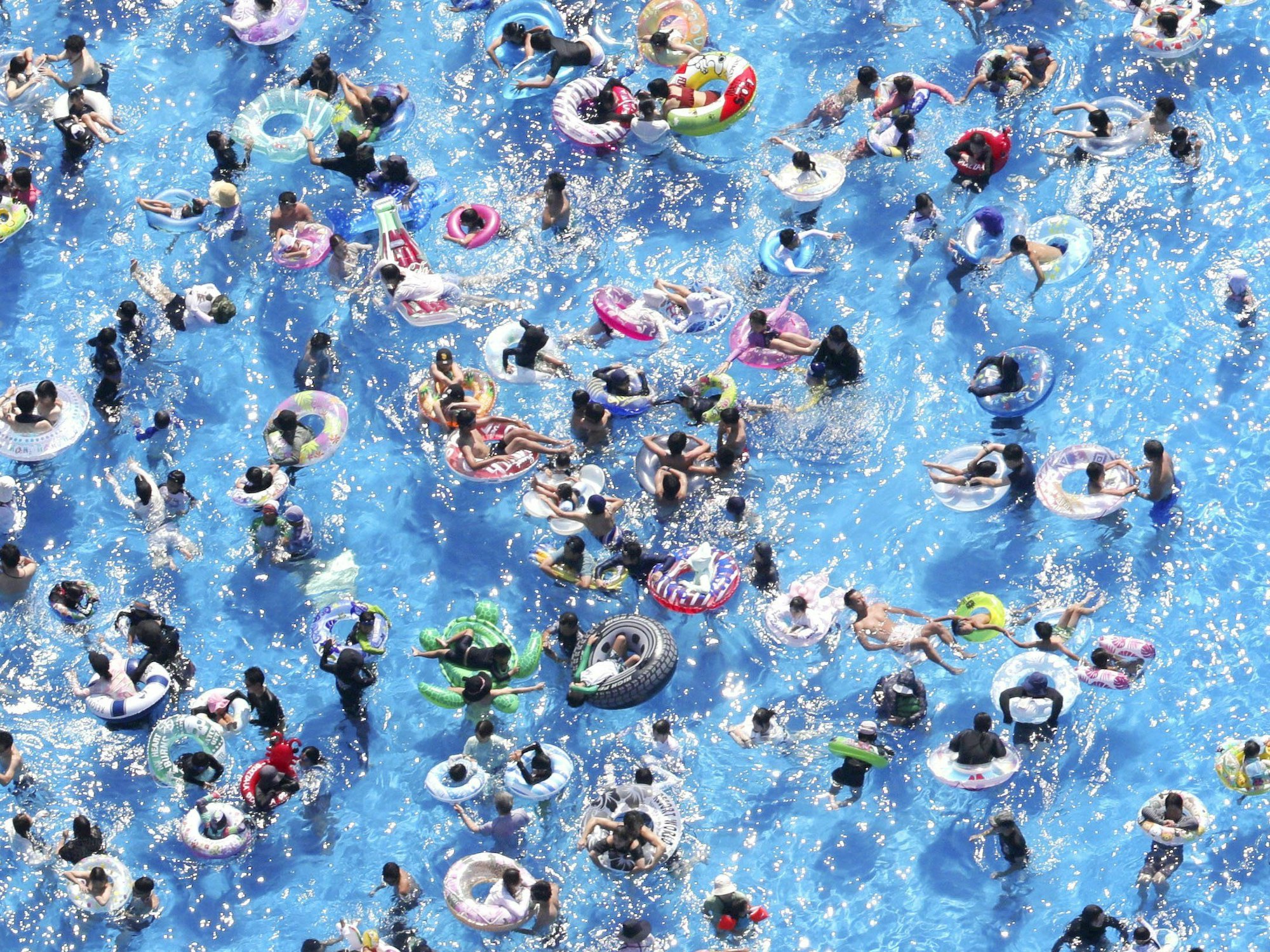 Menschen mit Schwimmreifen in einem Schwimmbad in Tokio (Japan).