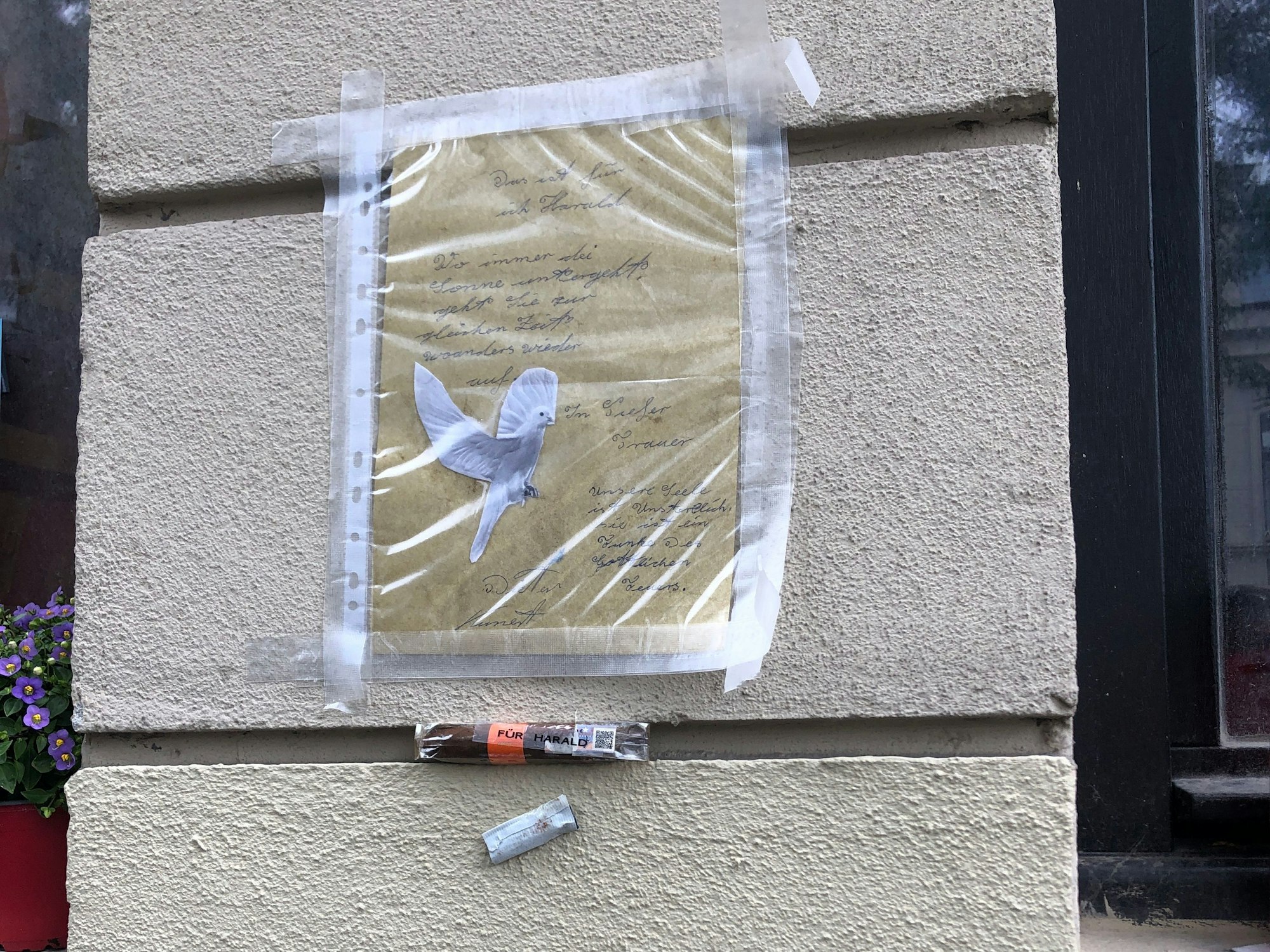 An einer Hauswand hängt ein Brief und eine Zigarre.