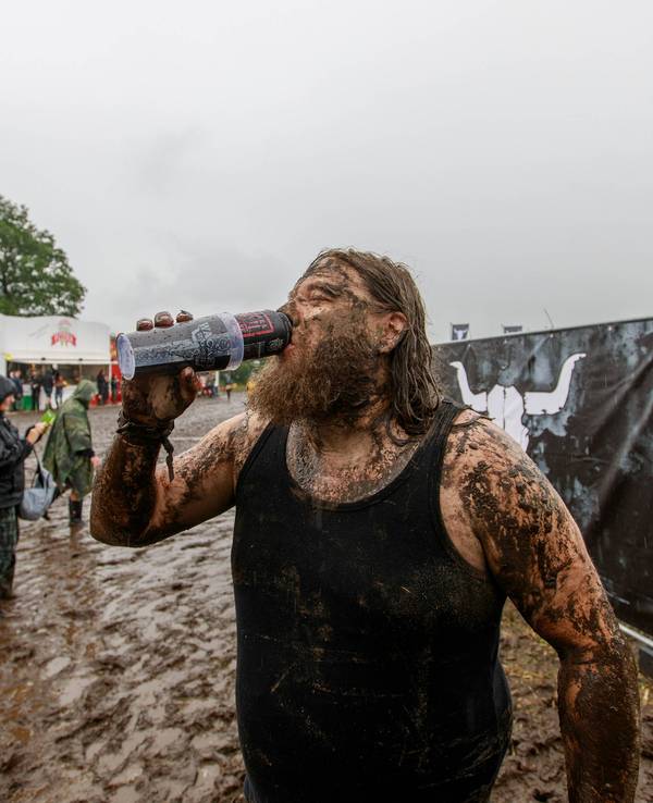 Ein Mann trotzt auf dem Gelände des Wacken Open Air dem Regen und Schlamm.