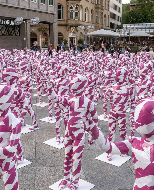 333 Kinderfiguren in purpur-weißem Flatterband vor dem Kölner Dom