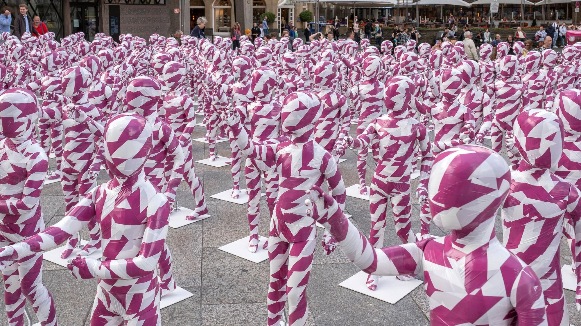 333 Kinderfiguren in purpur-weißem Flatterband vor dem Kölner Dom