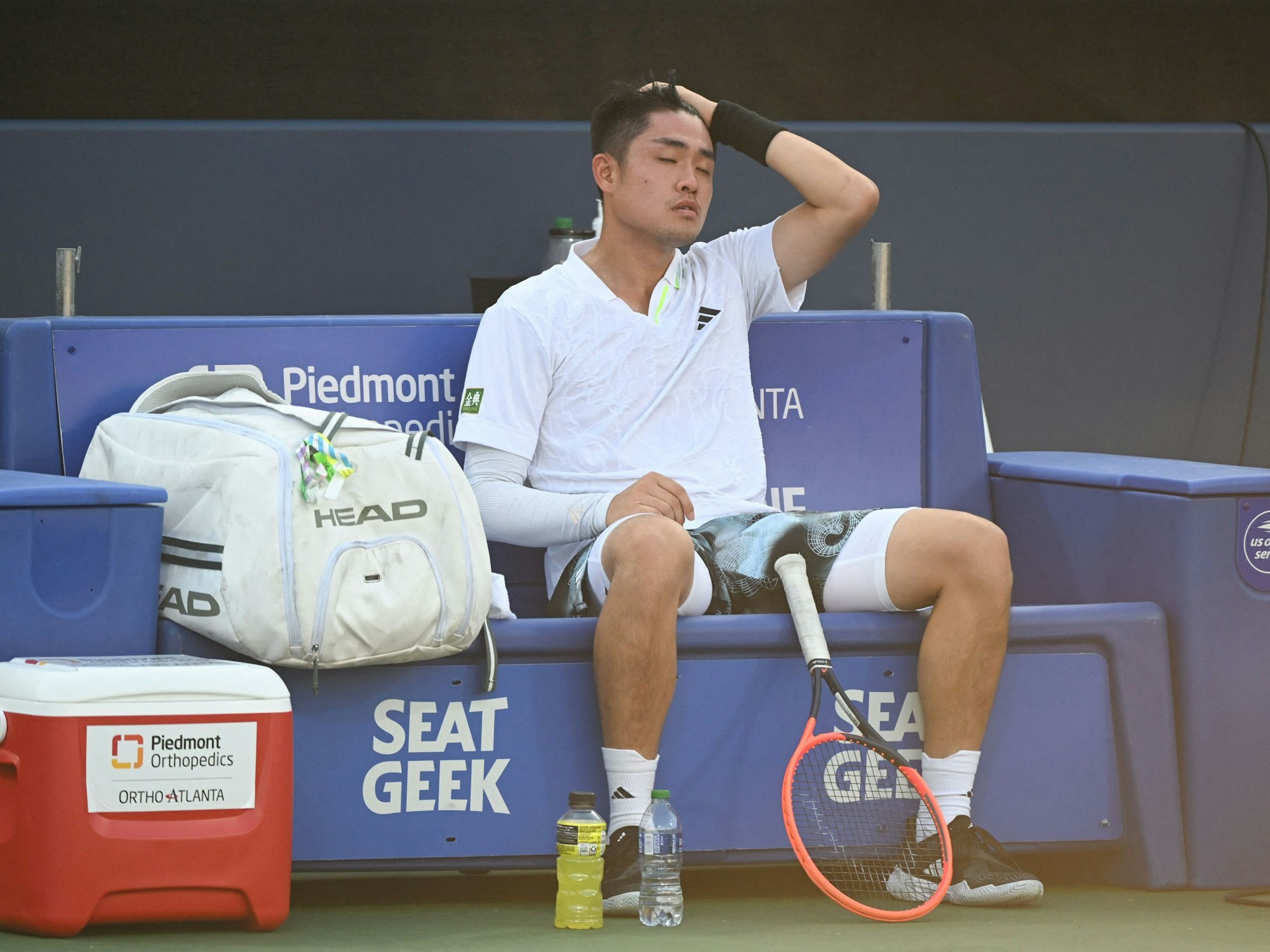 Wu Yibing sitzt beim ATP-Turnier in Atlanta erschöpft auf der Bank.