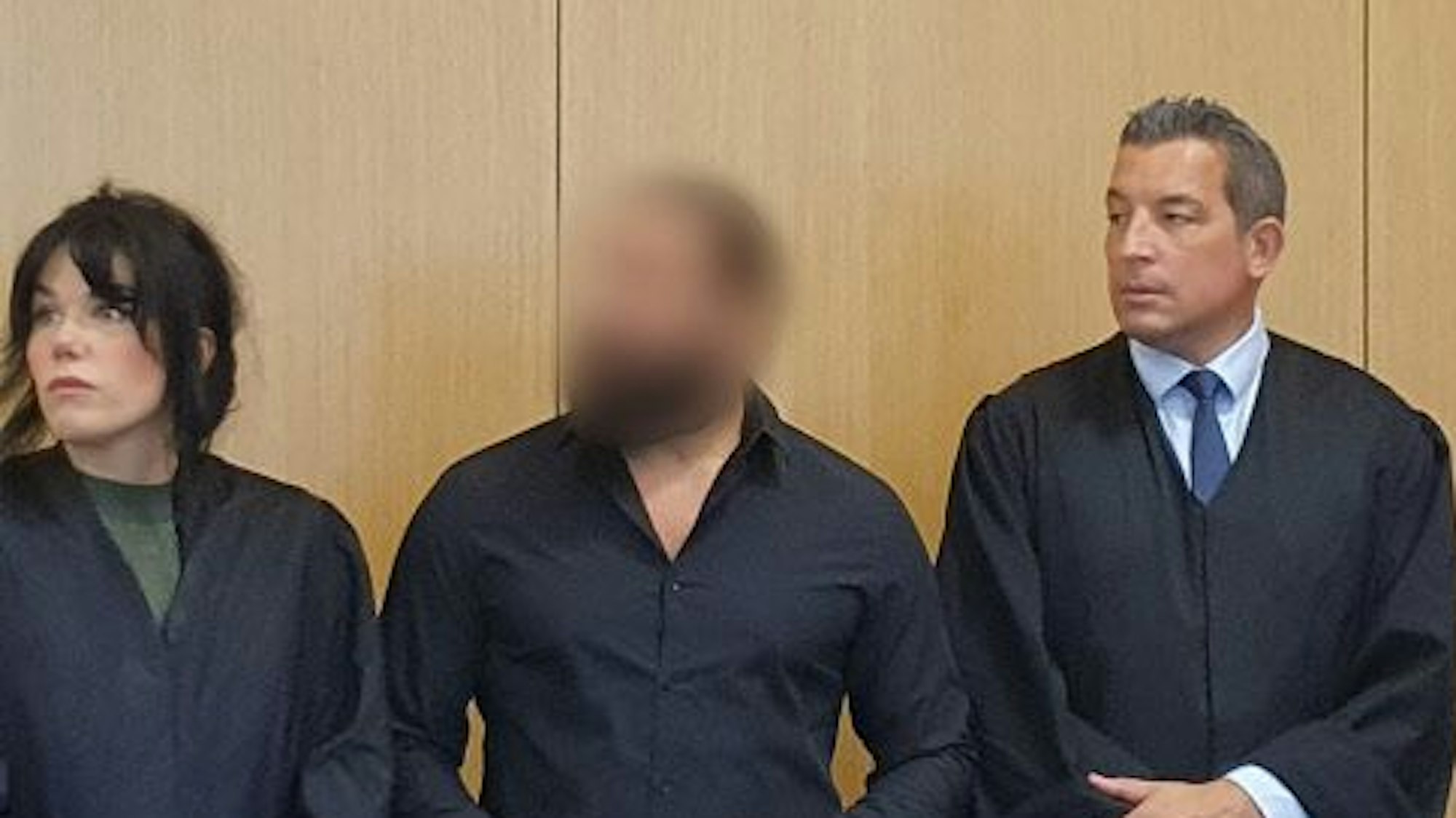 Der Angeklagte (M) steht am 1. August 2023 neben seiner Verteidigerin Franziska Ernst (l) und seinem Verteidiger Wolf Bonn im Gerichtssaal.