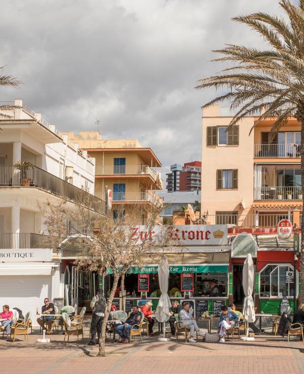 Deutsche Touristen sitzen in der bekannten Bar Zur Krone & Krone Stube und genießen einen Drink in der Sonne an der Playa de Palma auf Mallorca.