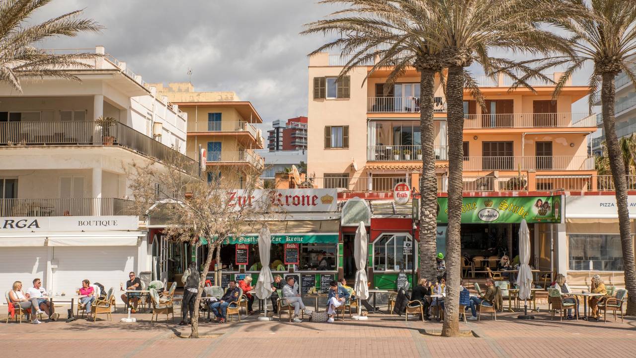 Deutsche Touristen sitzen in der bekannten Bar Zur Krone & Krone Stube und genießen einen Drink in der Sonne an der Playa de Palma auf Mallorca.
