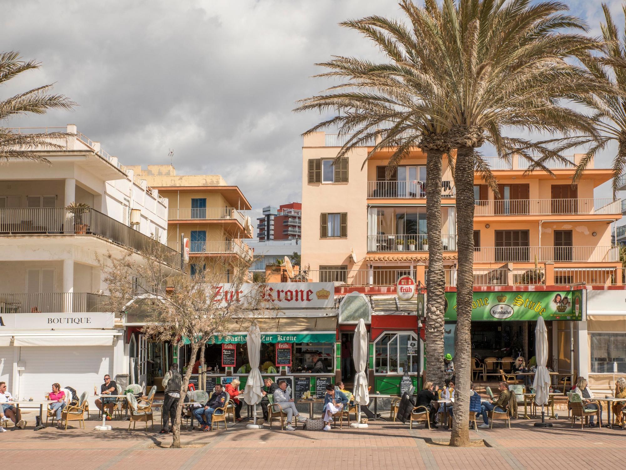 Deutsche Touristen sitzen in der bekannten Bar Zur Krone & Krone Stube und genießen einen Drink in der Sonne an der Playa de Palma auf Mallorca.