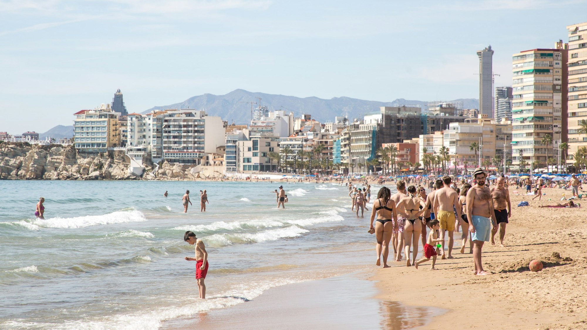 Menschen sonnen sich und schwimmen am Strand von Poniente in der Provinz Alicante.