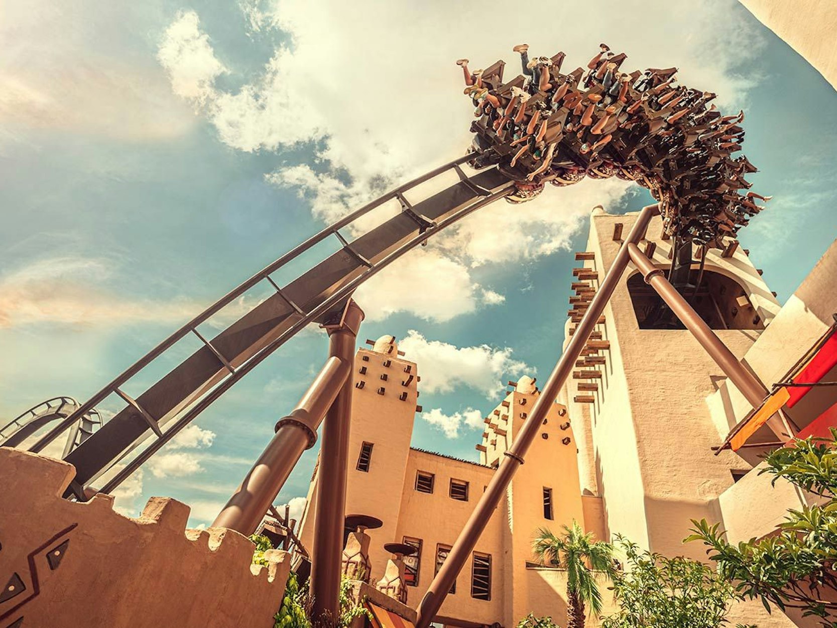 Eine Achterbahn fährt durch einen Freizeitpark.