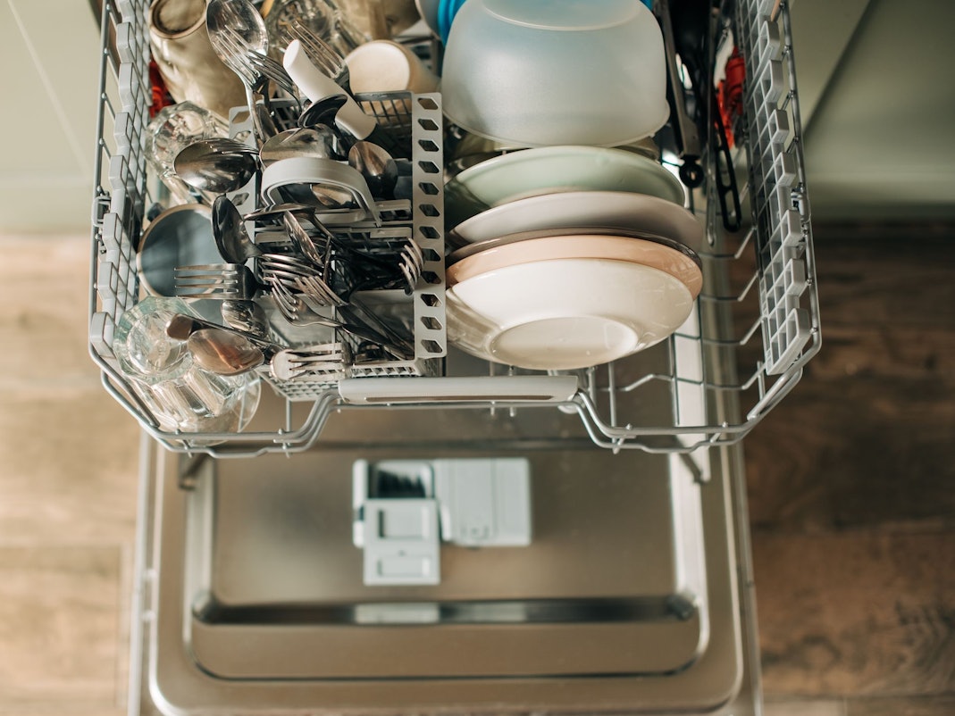 Auf dem Foto sieht man einen offenen Geschirrspüler mit sauberem Geschirr.