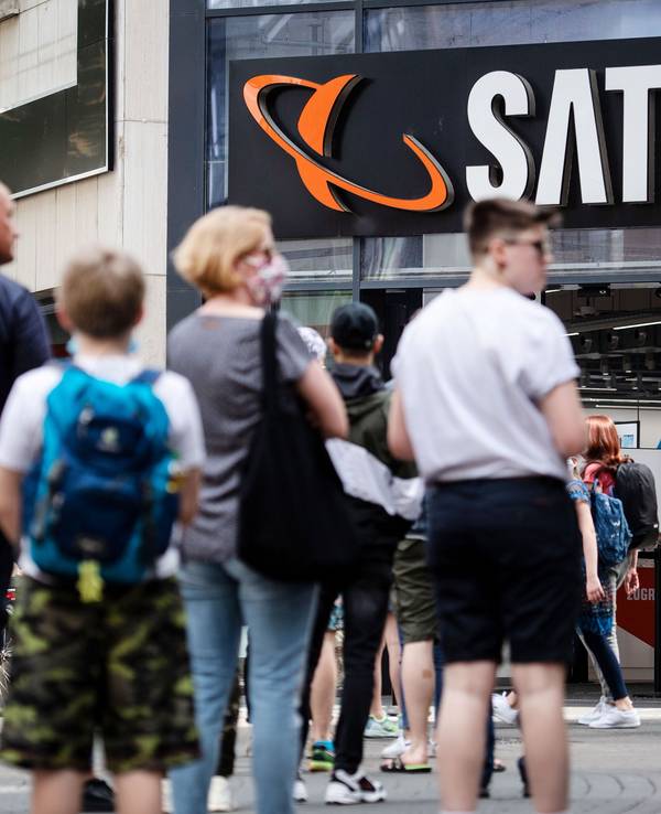 Menschen stehen in einer Warteschlange vor einer Filiale des Elektrohändlers Saturn an.
