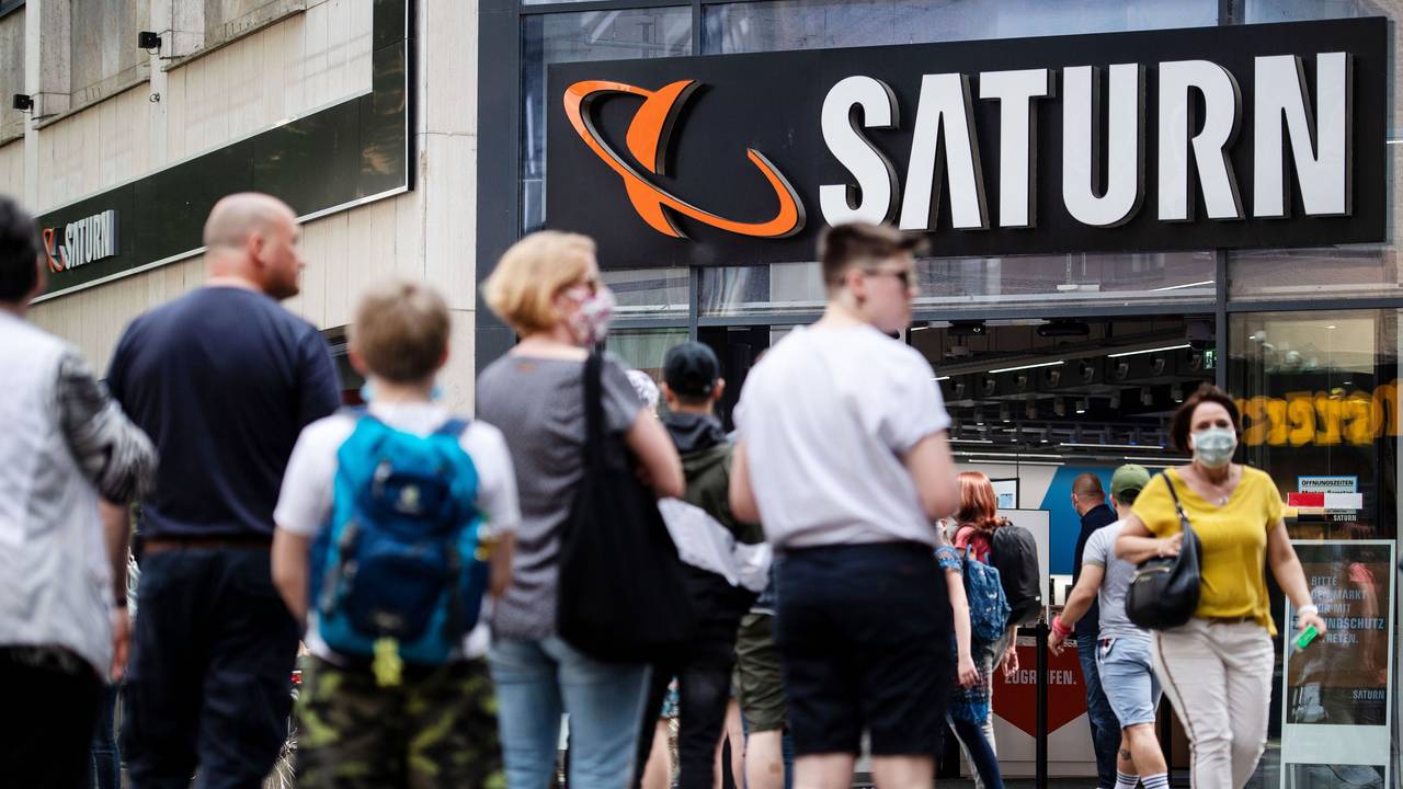 Menschen stehen in einer Warteschlange vor einer Filiale des Elektrohändlers Saturn an.