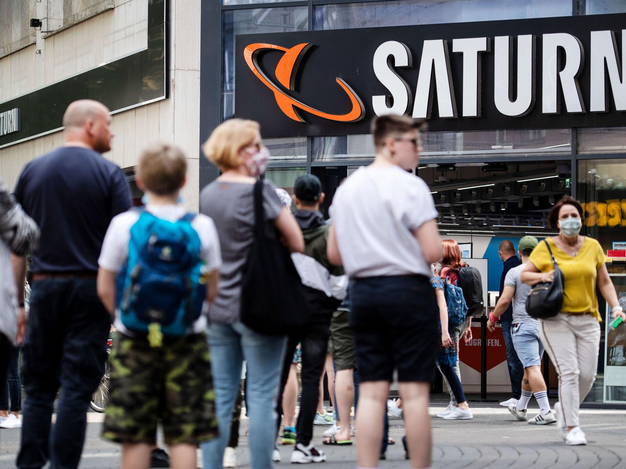 Menschen stehen in einer Warteschlange vor einer Filiale des Elektrohändlers Saturn an.