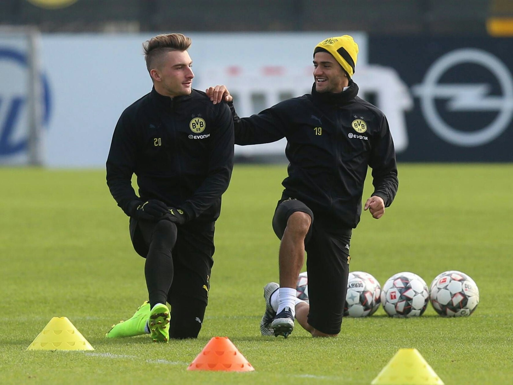 Die BVB-Profis Maximilian Philipp und Mahmoud Dahoud knien nebeneinander auf dem Trainingsplatz.
