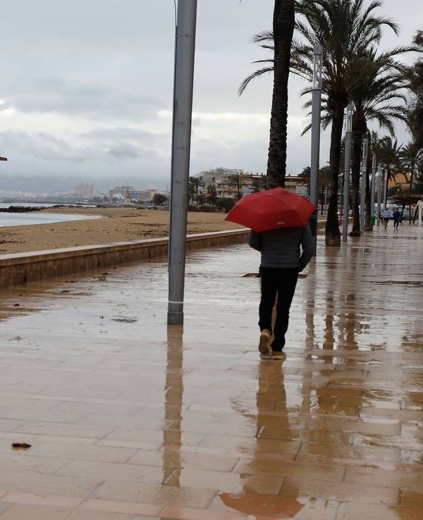 Ein Mann mit Regenschirm am Strand von Palma.