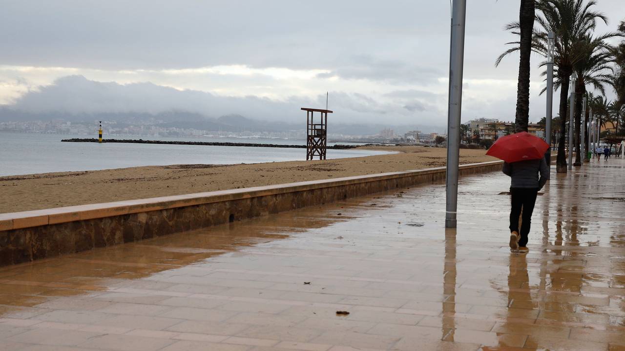 Ein Mann mit Regenschirm am Strand von Palma.